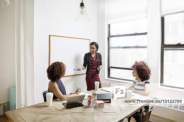 Confident businesswoman explaining strategy to female colleagues in board room
