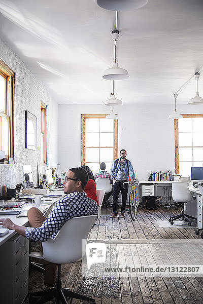 Business people working by desk in creative office