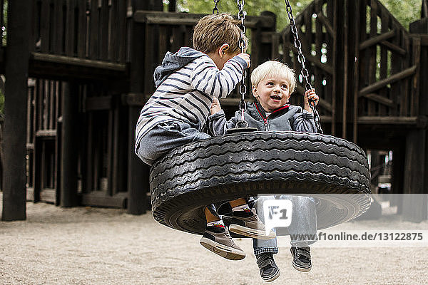 Happy brothers swinging in playground