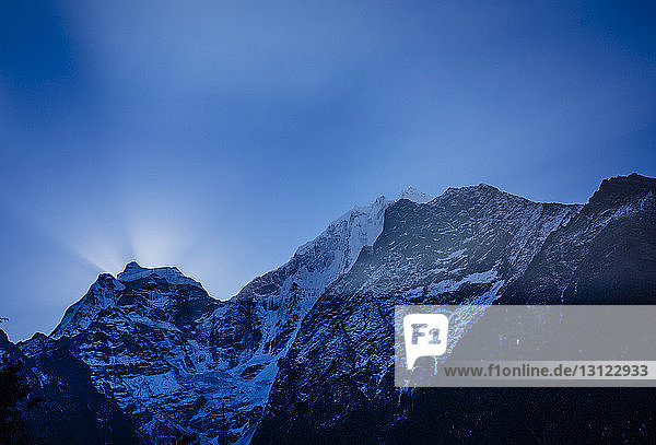 Tiefwinkelansicht von schneebedeckten Bergen gegen blauen Himmel in der Dämmerung