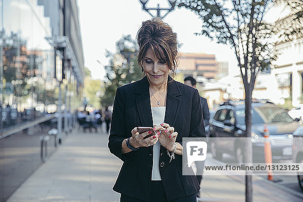 Geschäftsfrau benutzt Smartphone auf Fußweg