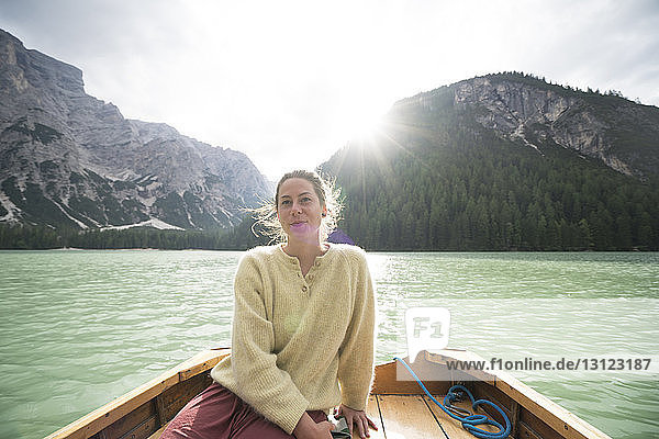 Frau sitzt im Boot auf dem Fluss inmitten eines Berges gegen den Himmel