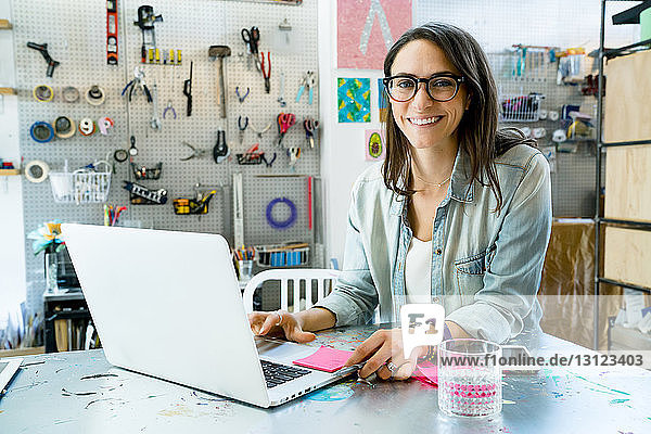 Portrait of happy businesswoman using laptop computer in office