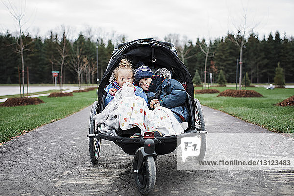 Geschwister im Kinderwagen auf der Straße gegen den Himmel