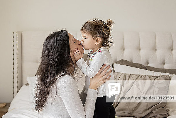 Liebende Mutter und Tochter küssen sich zu Hause auf den Mund
