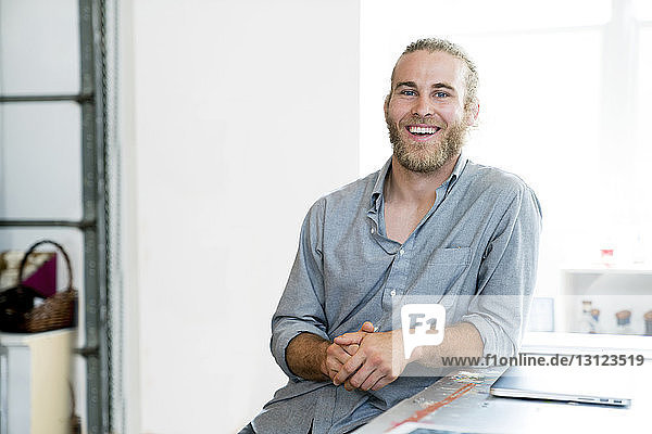 Porträt eines glücklichen Geschäftsmannes  der im Büro sitzt