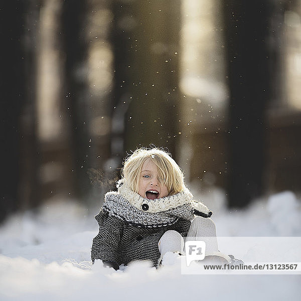 Portrait of cheerful girl playing in snow at park