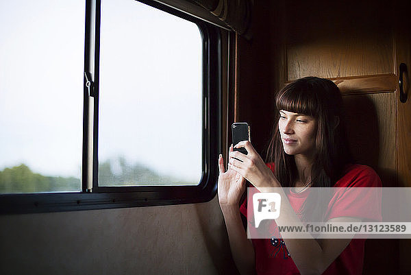 Frau fotografiert mit Smartphone während einer Reise im Wohnmobil