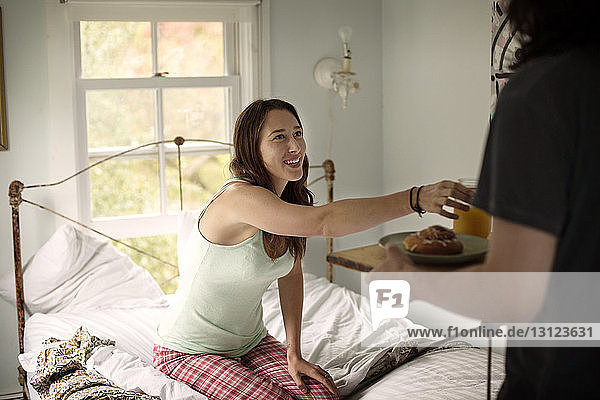 Midsection of man serving breakfast to woman in bedroom
