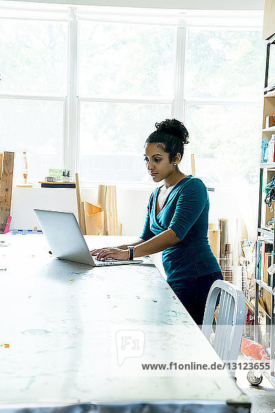 Geschäftsfrau benutzt Laptop-Computer  während sie im Büro am Tisch sitzt