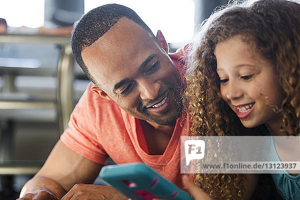 Nahaufnahme von Vater und Tochter beim Spielen eines Videospiels  während sie zu Hause liegen