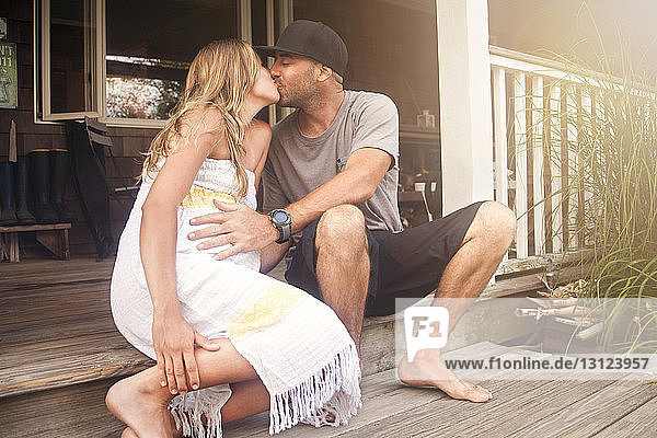 Paar küsst sich  während es auf der Veranda des Hauses sitzt