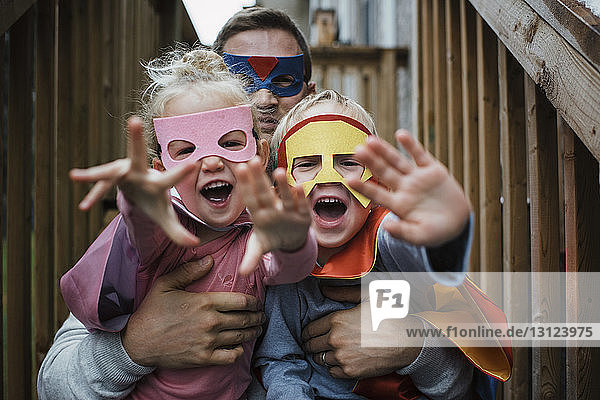 Porträt von Kindern mit Vater in Superhelden-Kostümen