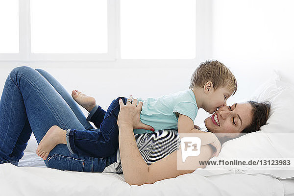 Loving son kissing mother on bed at home