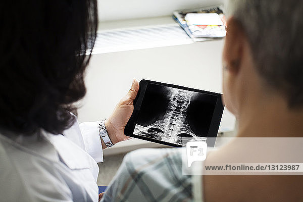 Ärztin zeigt Patientin Röntgenbild auf Tablet-Computer