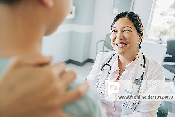 Cheerful pediatrician looking at girl in medical examination room