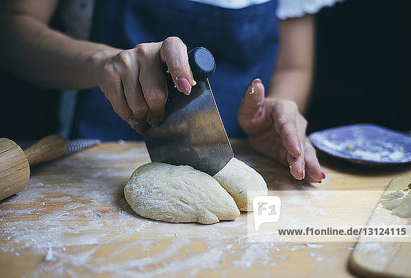 Mitschnitt einer Frau  die an der Küchentheke Brotteig schneidet