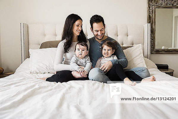 Happy family sitting on bed at home