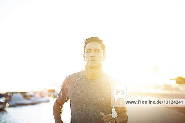Entschlossener männlicher Athlet  der bei Sonnenuntergang auf dem Steg läuft