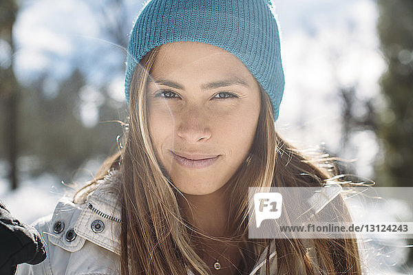 Porträt einer lächelnden Frau mit Strickmütze  die im Winter auf dem Feld steht