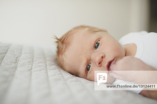 Close-up portrait of baby boy lying on bed at home