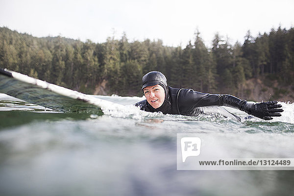 Porträt einer Frau  die auf einem Surfbrett im Meer liegt
