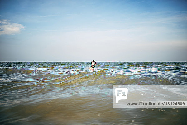 Junge schwimmt im Meer gegen den Himmel