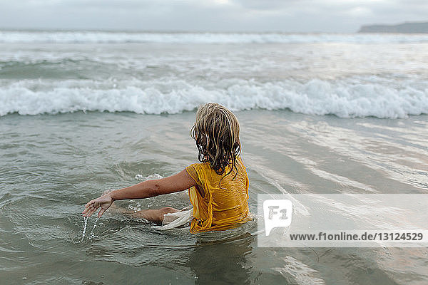 Carefree girl sitting in sea at beach
