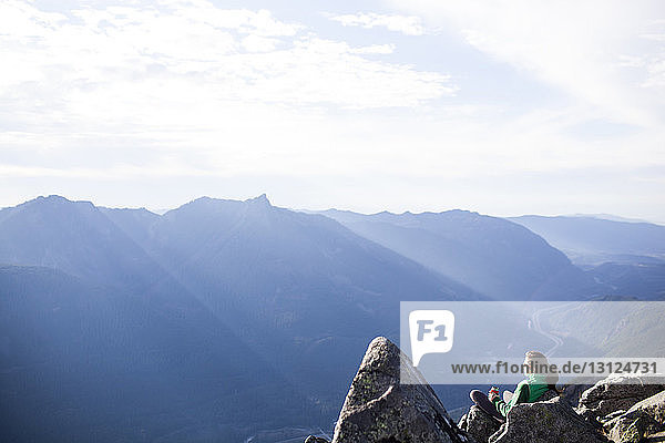 Hochwinkelaufnahme einer Frau  die sich auf Felsen gegen eine Bergkette entspannt