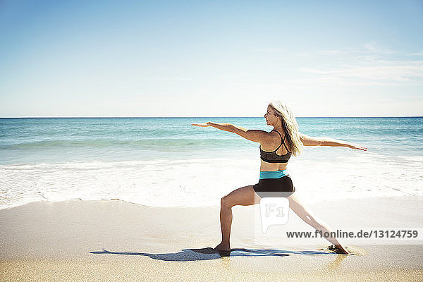 Rückansicht einer entschlossenen Frau  die in Warrior-2-Pose am Delray-Strand Yoga praktiziert