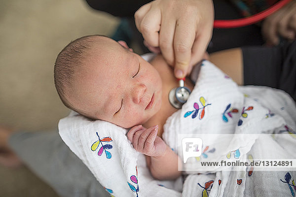 Abgetrennte Hand der Hebamme  die das von der Mutter zu Hause getragene Neugeborene untersucht
