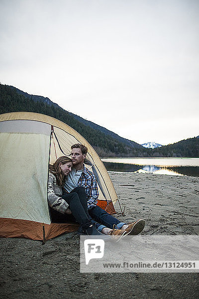 Young couple sitting in tent on lakeshore at Silver Lake Provincial Park