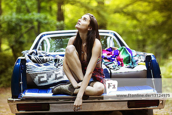 Nachdenkliche Frau sitzt im Pick-up im Wald