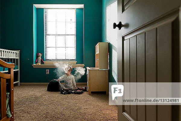 Junge spielt mit Dampfmaschine  während er zu Hause auf dem Teppich sitzt