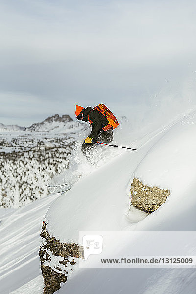 Seitenansicht eines Wanderers mit Rucksack auf einem schneebedeckten Berg