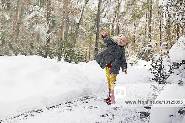 Cheerful girl playing on snow covered field at park