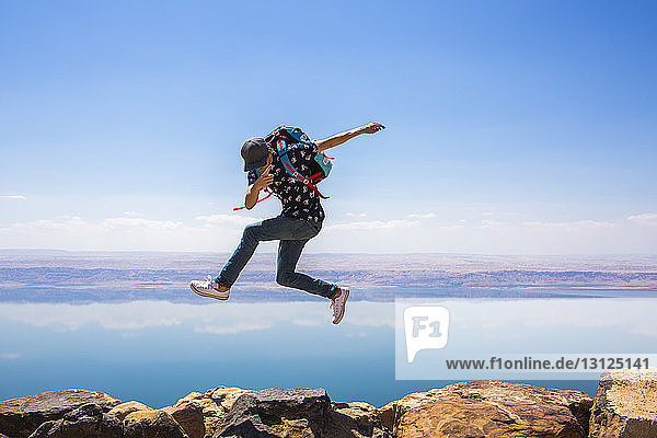 Happy woman jumping on mountain against sea