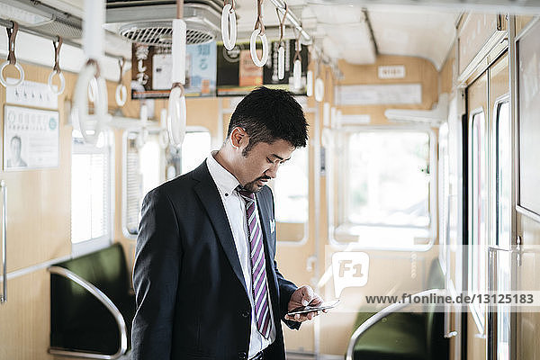 Geschäftsmann benutzt Smartphone im Zug stehend