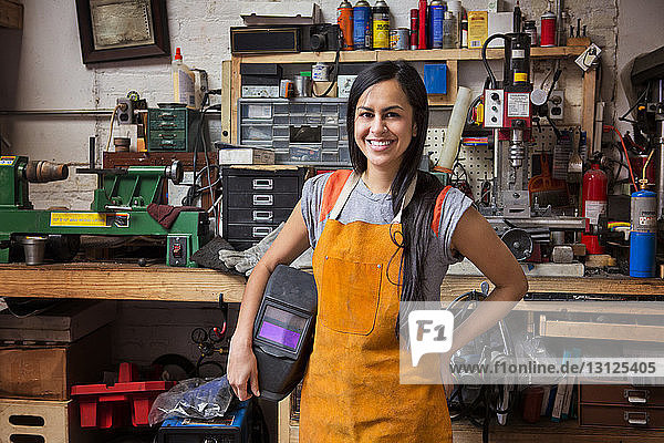 Portrait of happy female mechanic wearing apron in workshop