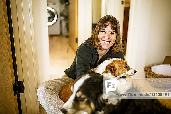 Portrait of woman with dogs sitting on floor at home