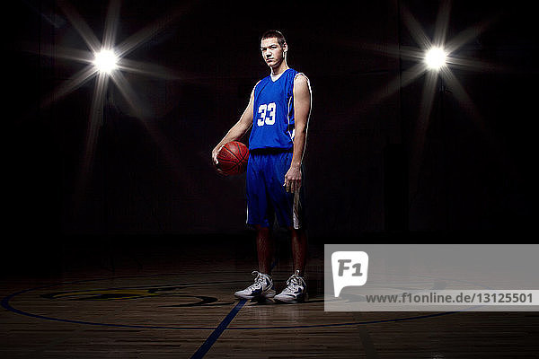 Porträt eines Basketballspielers im beleuchteten Spielfeld stehend