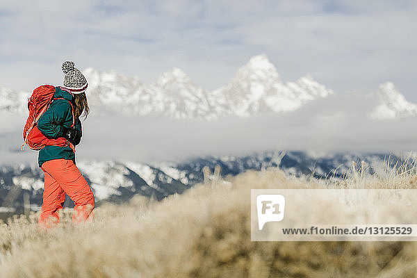 Wanderin mit Rucksack mit Blick auf schneebedeckte Berge