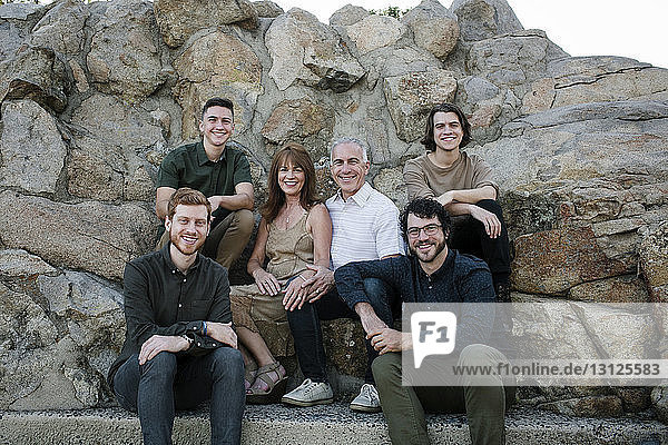 Porträt einer glücklichen Familie  die im Park vor Felsformationen sitzt