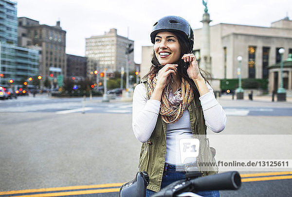 Frau mit Helm beim Stehen mit Fahrrad in der Stadt