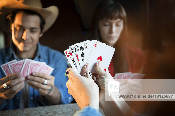 Ausgeschnittenes Bild einer Frau  die Karten hält  während sie mit Freunden im Wohnmobil spielt