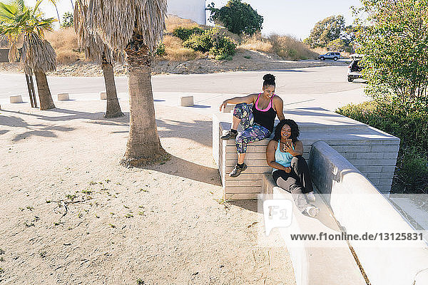 High angle view of Woman showing smart phone to female friends while sitting on concrete bench