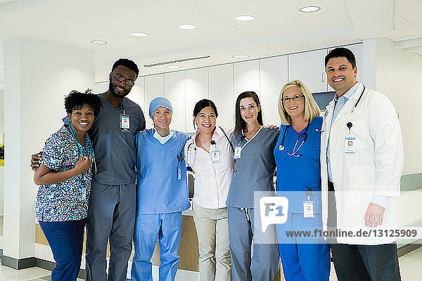 Portrait of cheerful doctors and nurses standing in hospital corridor