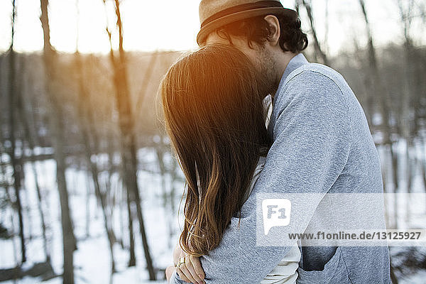 Seitenansicht eines Paares  das sich im Winter umarmt