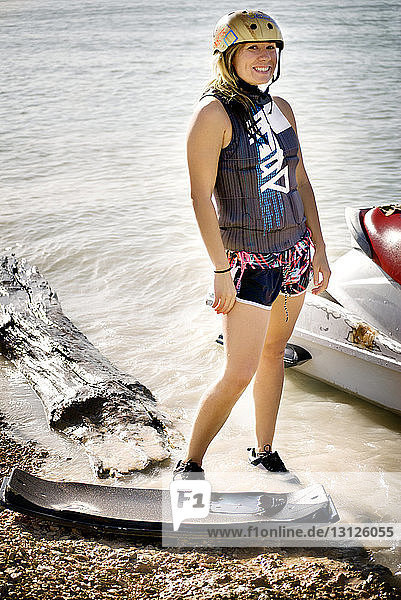 Porträt einer Frau  die mit einem Düsenboot am Ufer steht