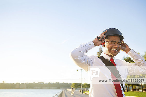 Low angle view of businessman wearing cycling helmet while standing against sky